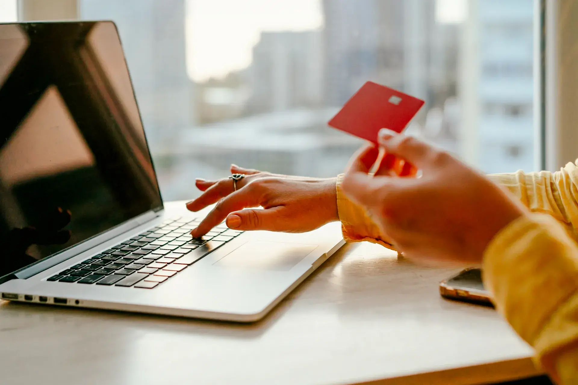 a hang typing on a laptop keyboard while holding their credit card to read
