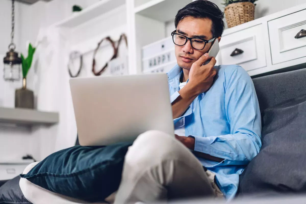 pessoa no computador e falando ao telefone