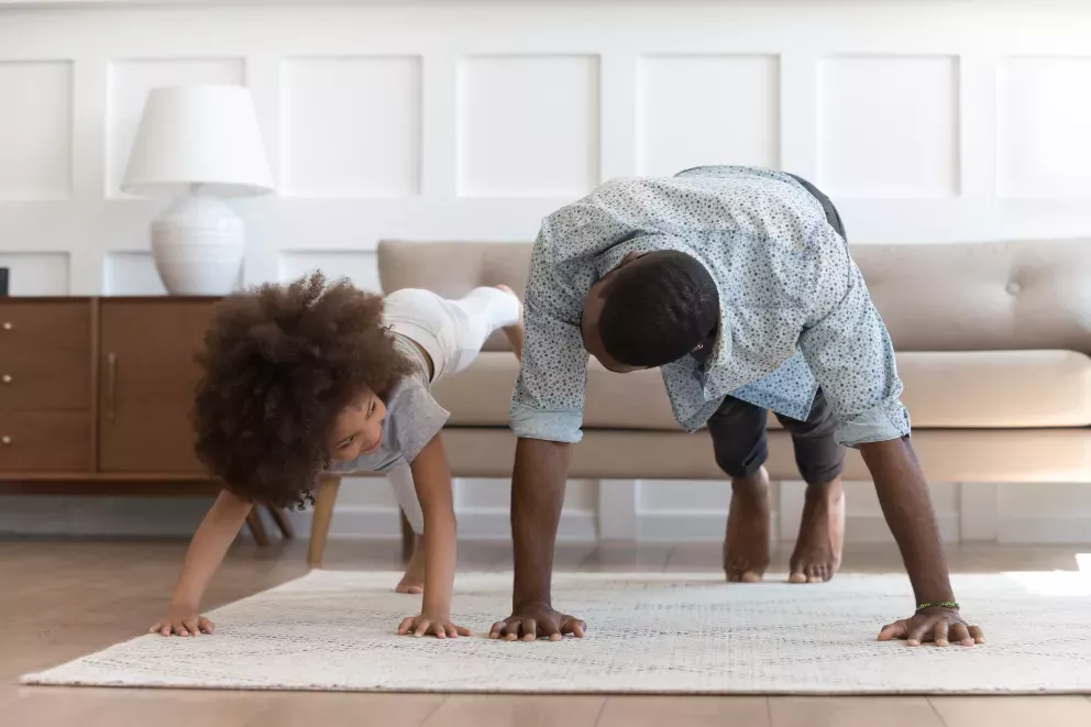 Pai e filha fazendo flexão dentro de casa