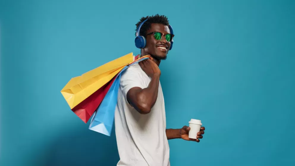 Homem segurando um café e sacos de compras