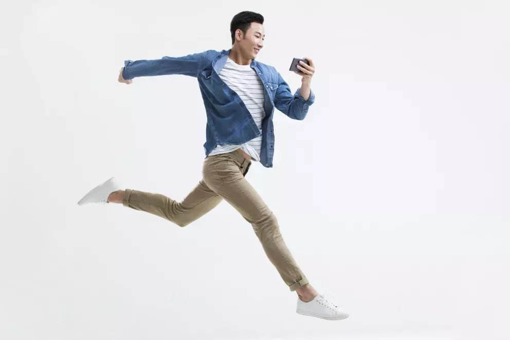 homem saltitante olhando para o celular