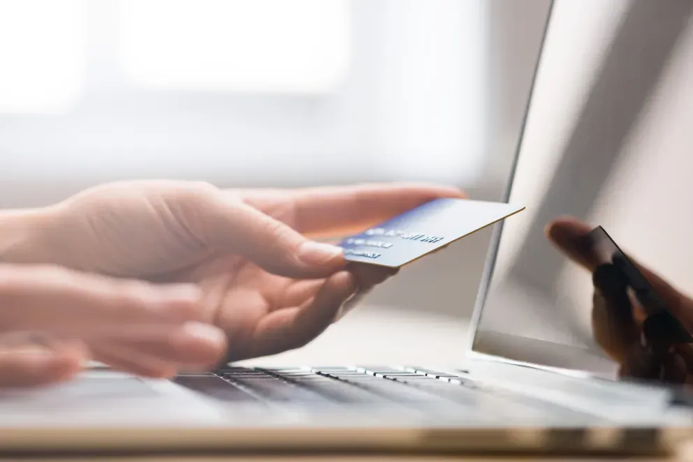 hands typing on laptop while holding credit card hands typing on laptop while holding credit card