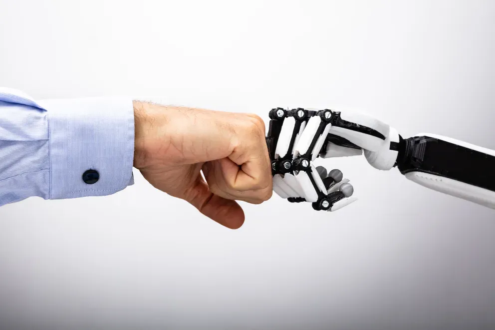 mão humana e mão robô batendo punhos
