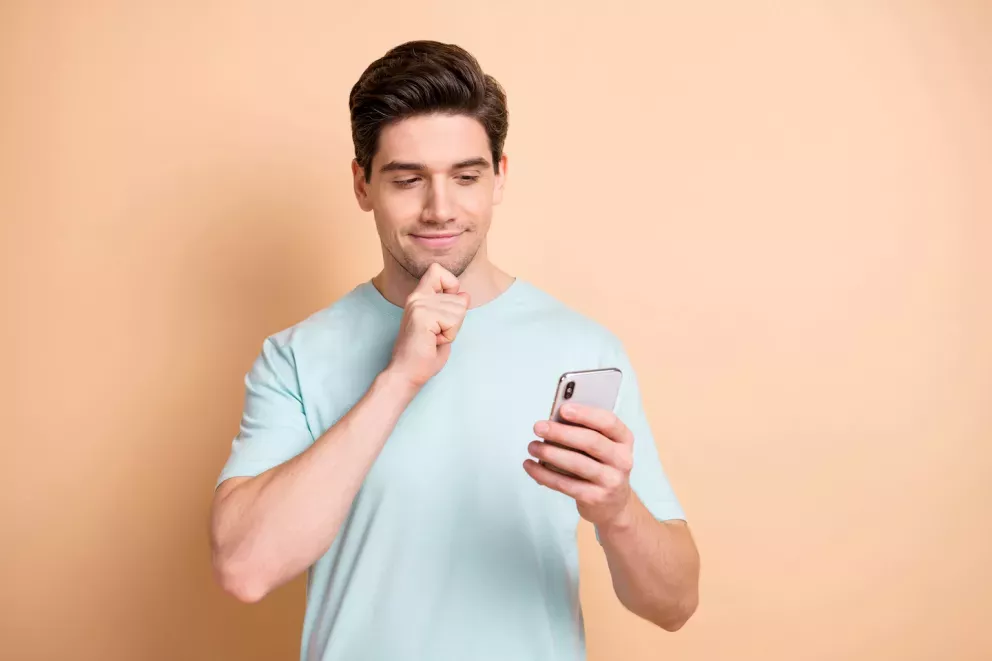 Homem olhando celular com expressão questionável