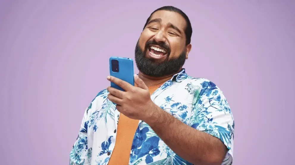 Homem rindo e olhando para um telefone