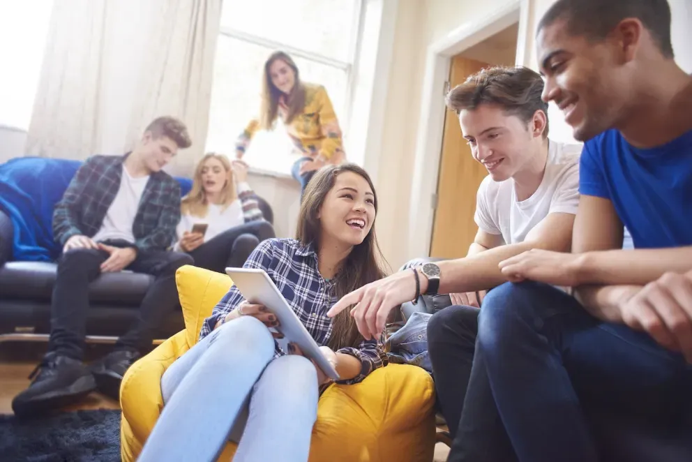 Grupo de alunos sorrindo e trabalhando em um projeto juntos
