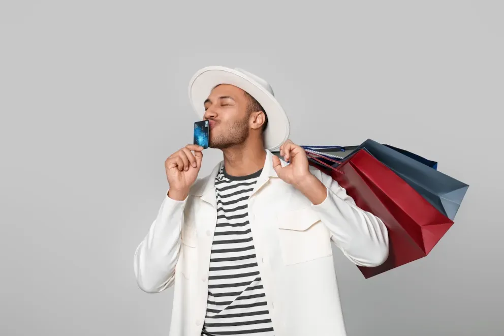 happy man holding shopping bags and kissing credit card