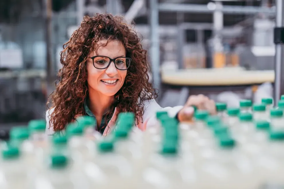 Mulher sorridente trabalhando em uma fábrica de refrigerantes