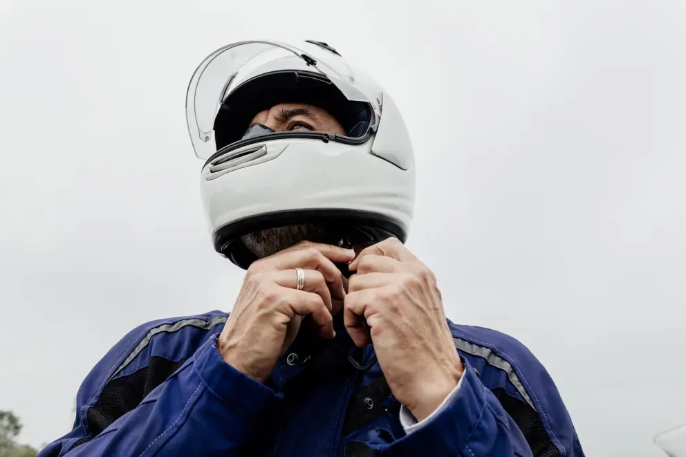 Person wearing helmet and blue jacket adjusting the helmet with both hands.