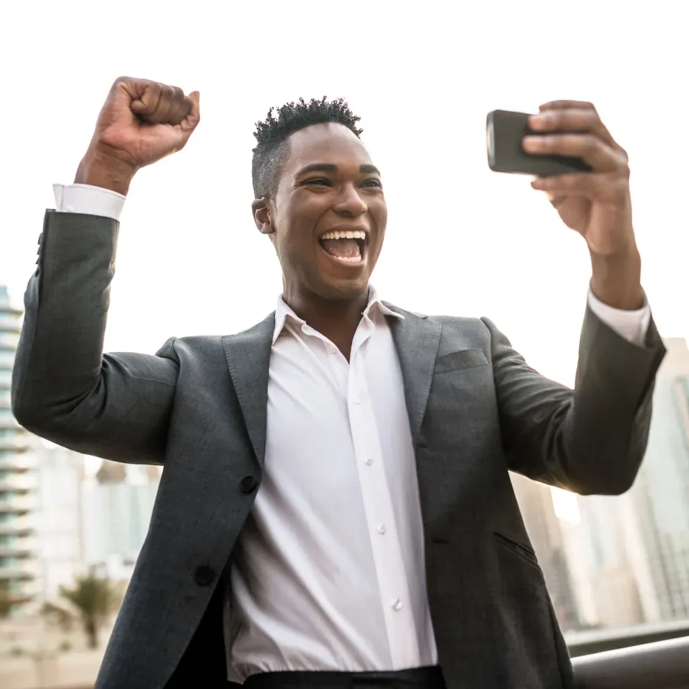 homem de negócios sorrindo e aplaudindo segurando telefone