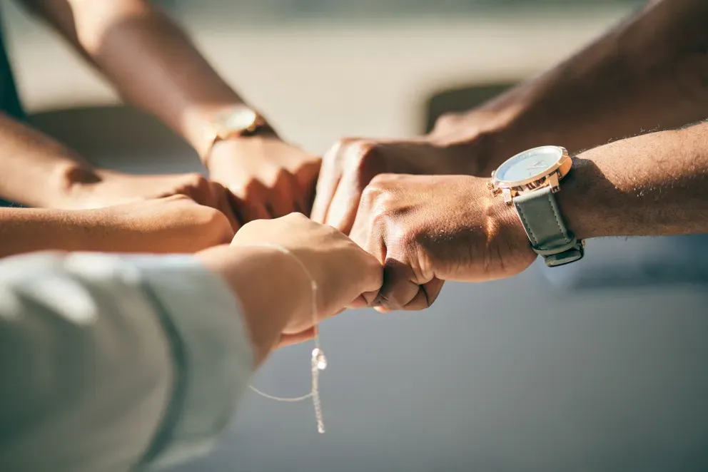 Um grupo de pessoas juntando as mãos em uma demonstração de trabalho em equipe e união. Um grupo de pessoas juntando as mãos em uma demonstração de trabalho em equipe e união.