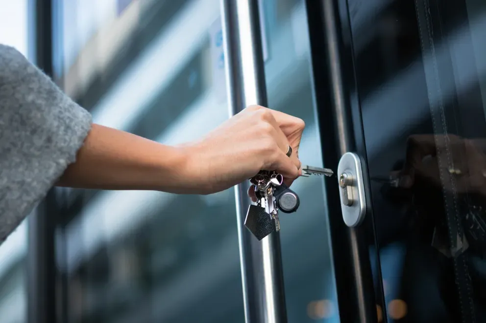 Inserção manual de uma chave em uma fechadura de porta de vidro moderna. Inserção manual de uma chave em uma fechadura de porta de vidro moderna.