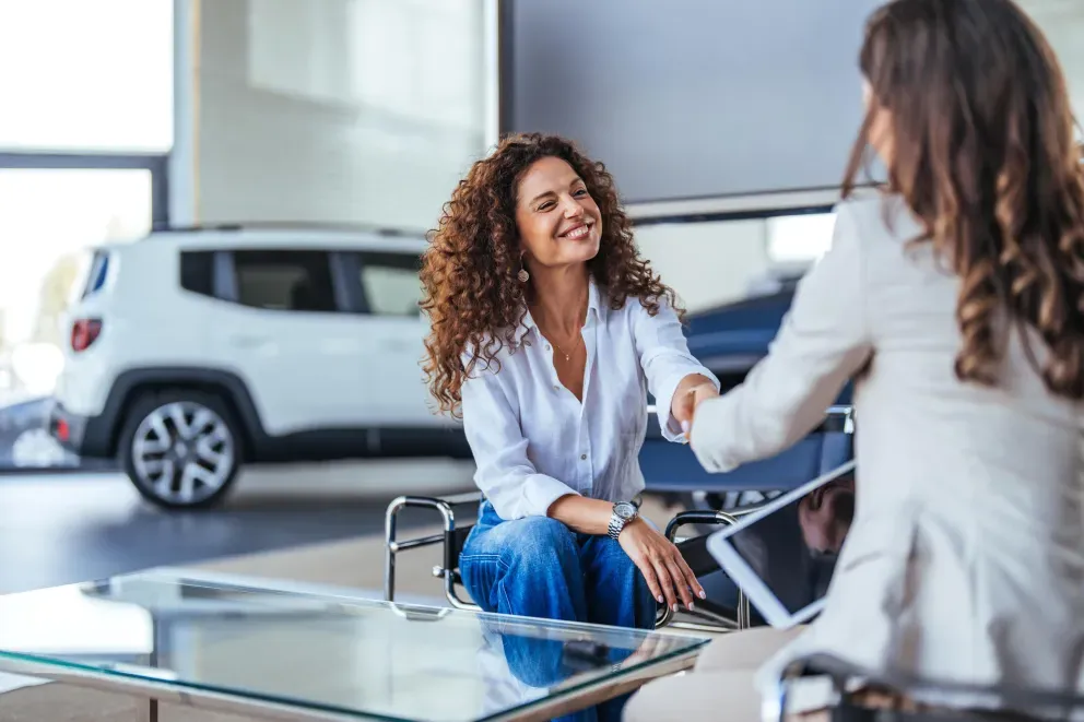 Two women sitting and talking in a modern indoor setting,smiling as they face eachother.
