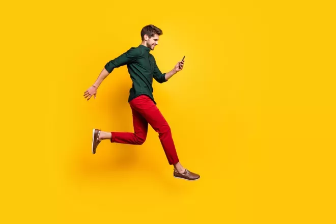 Homem pulando olhando para o telefone