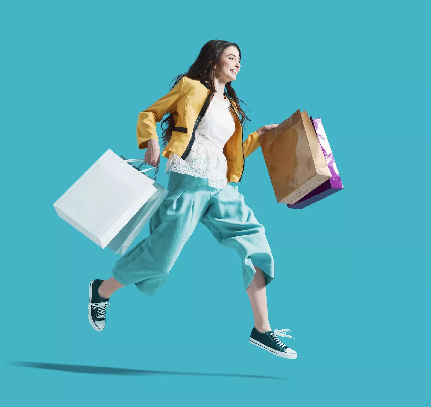 Mulher pulando com sacolas de compras