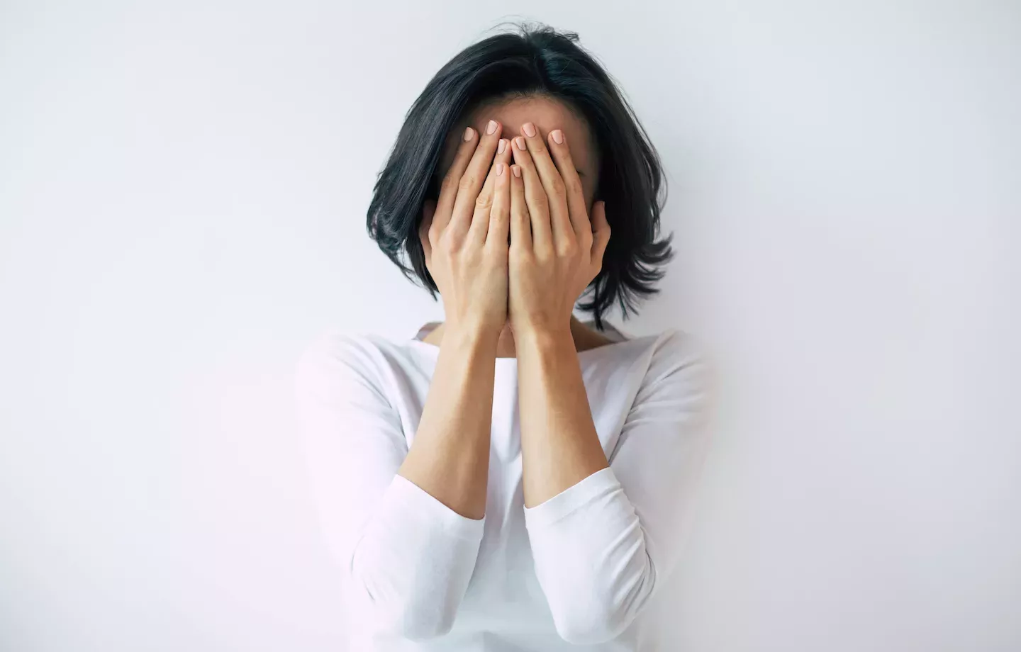 Mulher se escondendo atrás das mãos