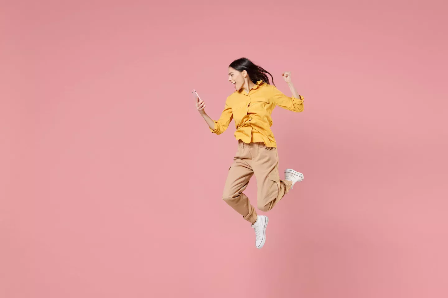 Mulher pulando olhando para um telefone