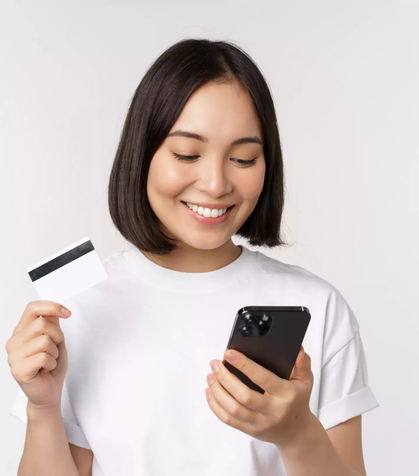 Mulher olhando para um telefone segurando um cartão de crédito