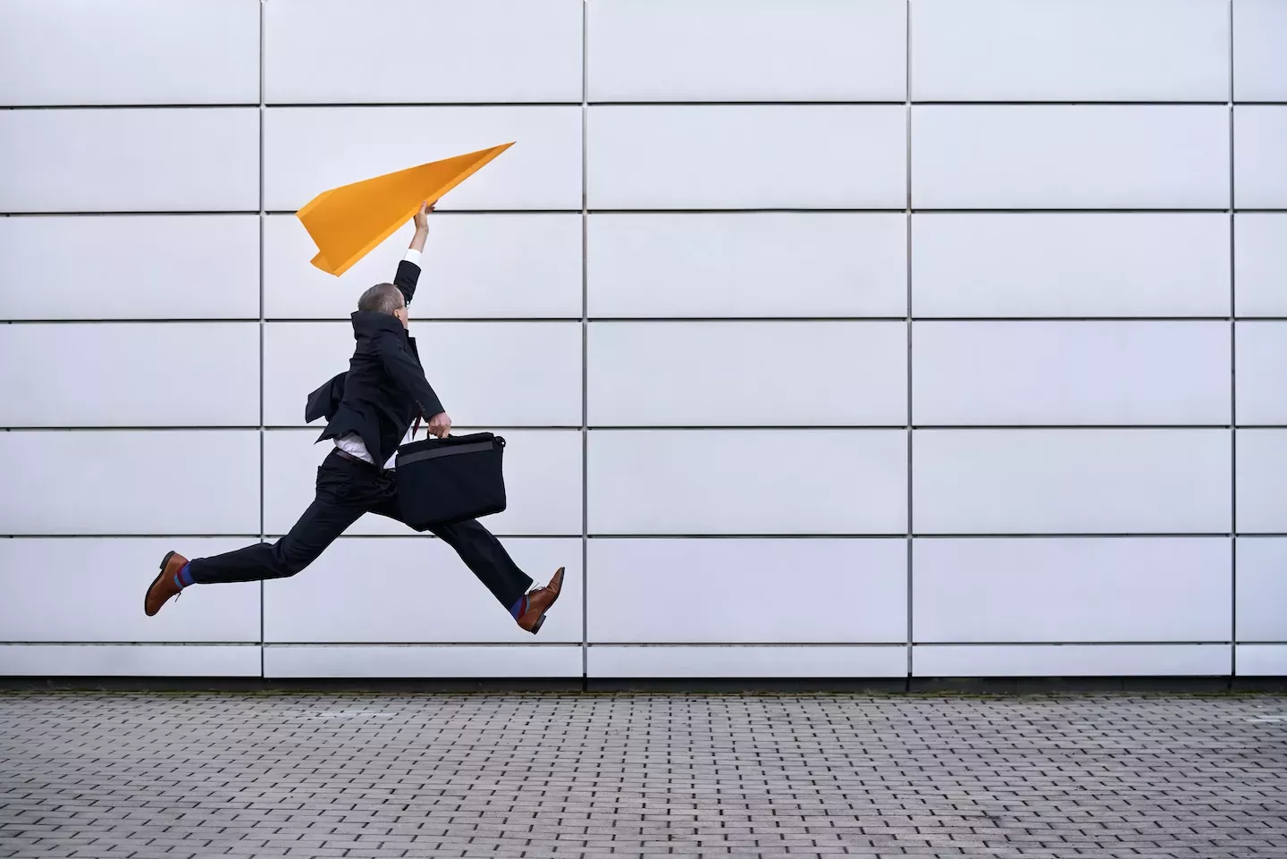 Homem pulando com um avião de papel