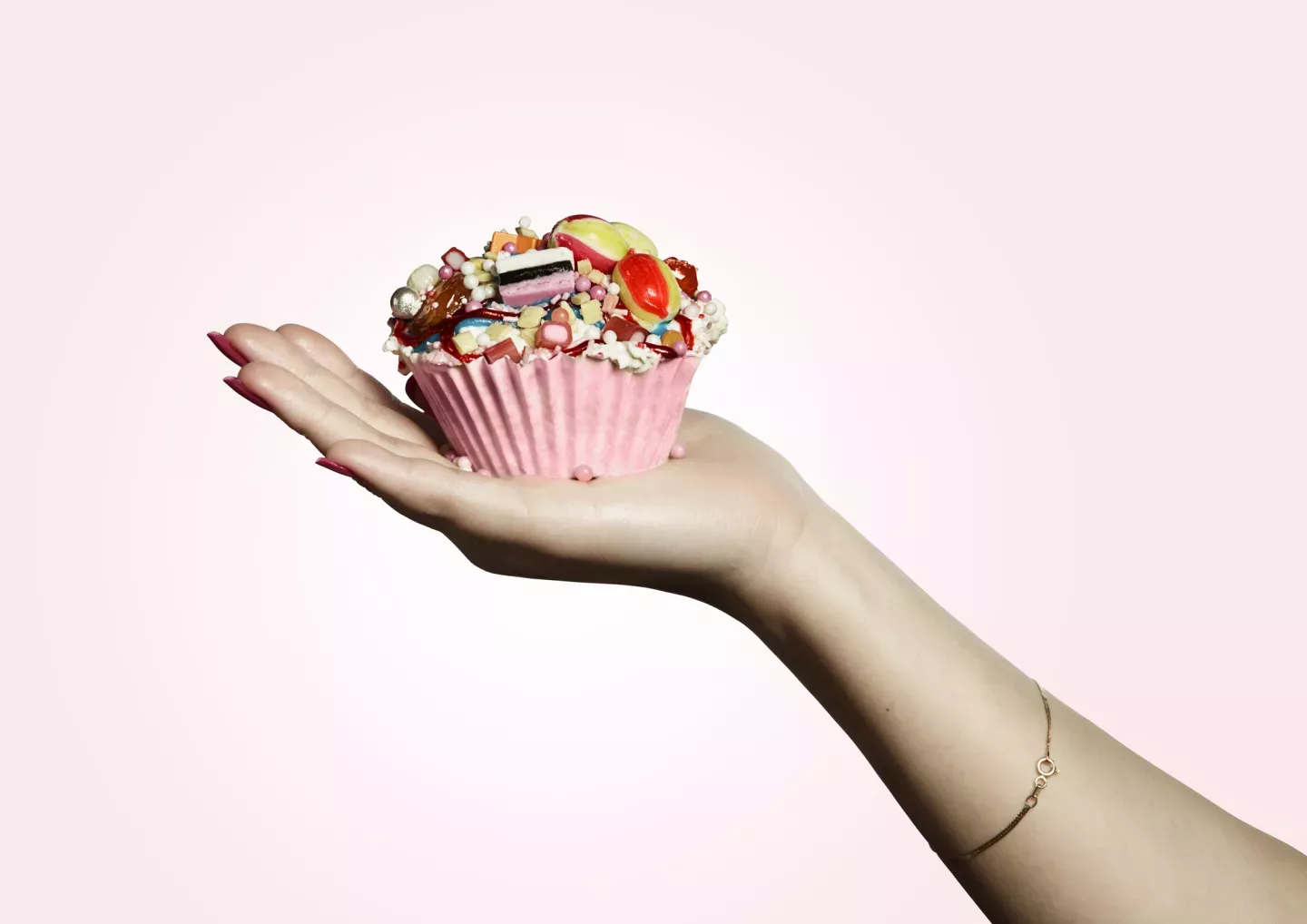 close up de pessoa segurando cupcake com cobertura de doces