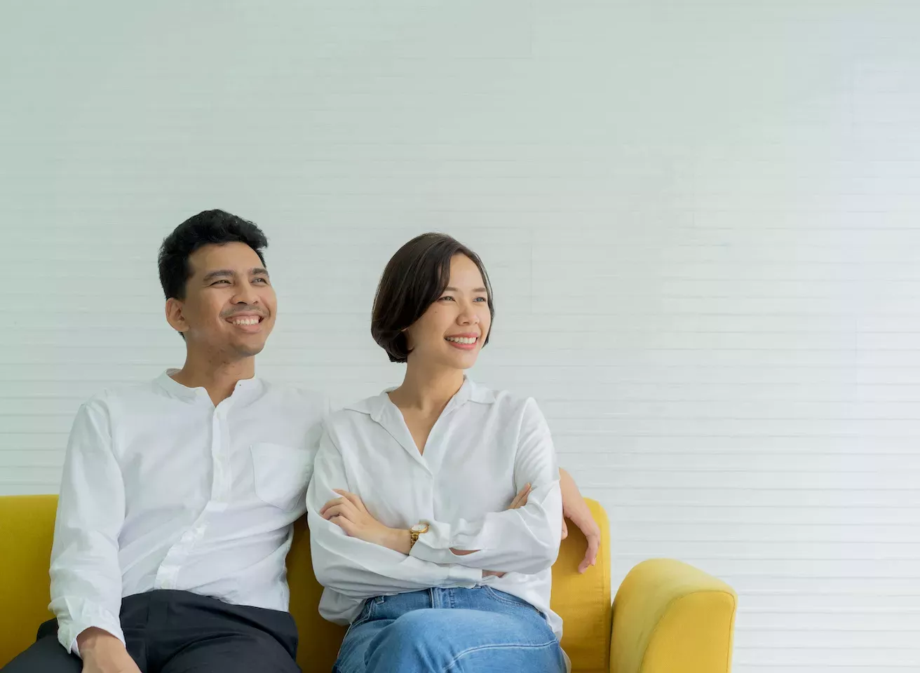 Casal feliz sentado em um sofá amarelo