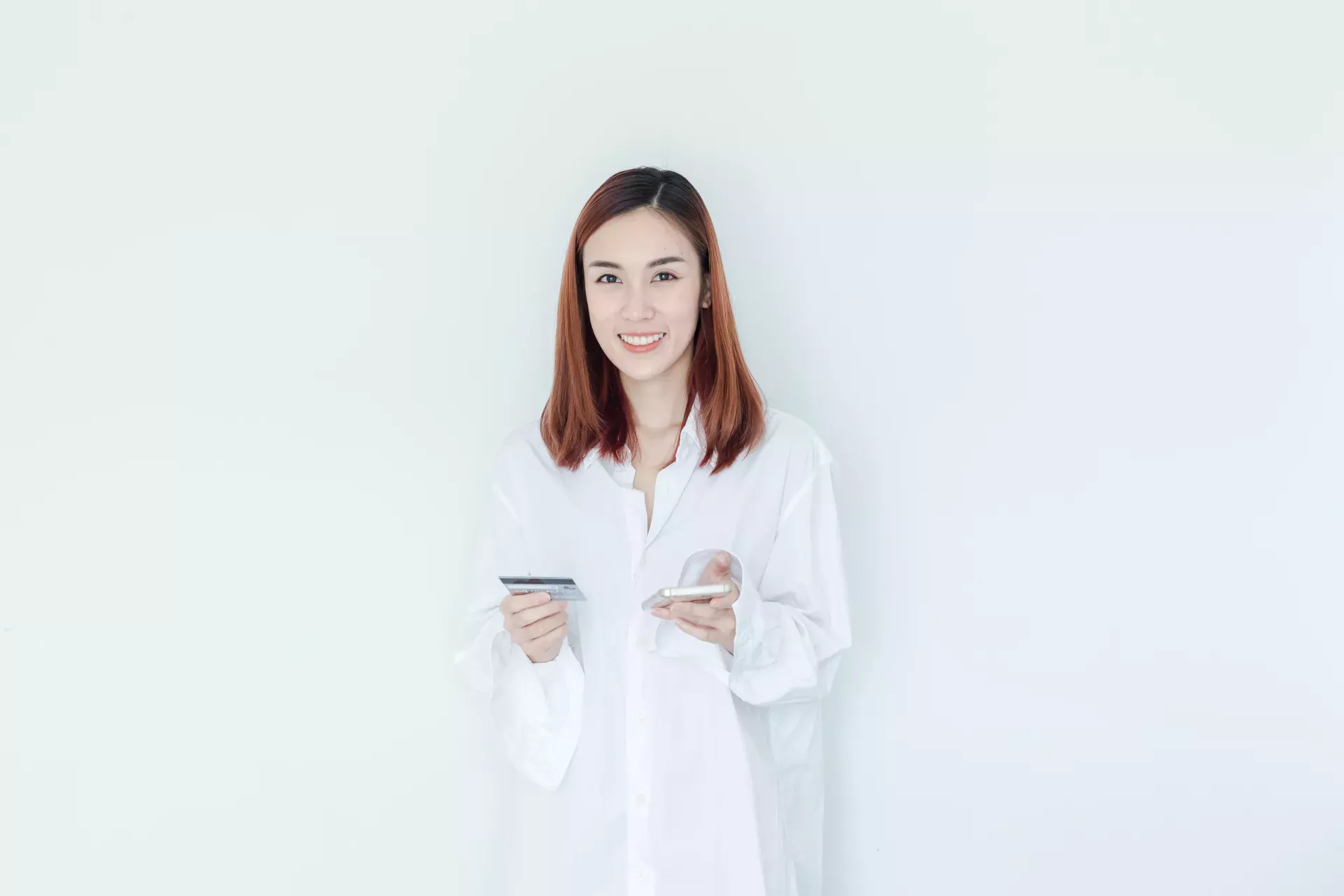 Mulher sorridente segurando o telefone celular e o cartão de crédito