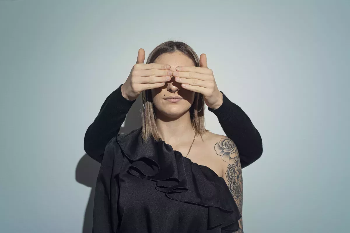 Frau mit Händen, die sich die Augen zuhalten