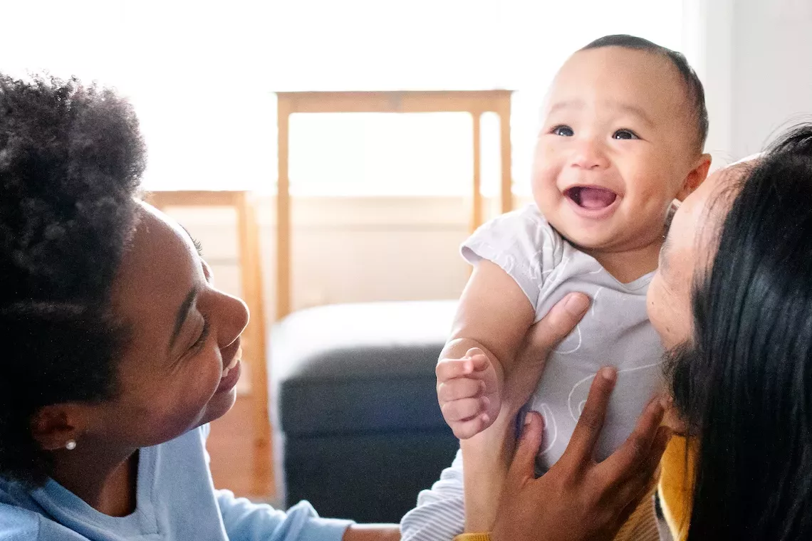 family holding newborn baby and smiling