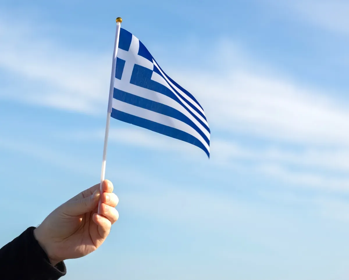Hand hält griechische Flagge am Himmel Hand hält griechische Flagge am Himmel