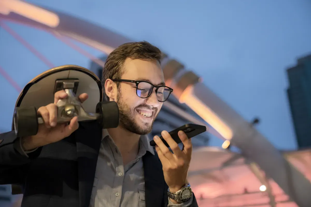 Junger Geschäftsmann mit Skateboard und Handy