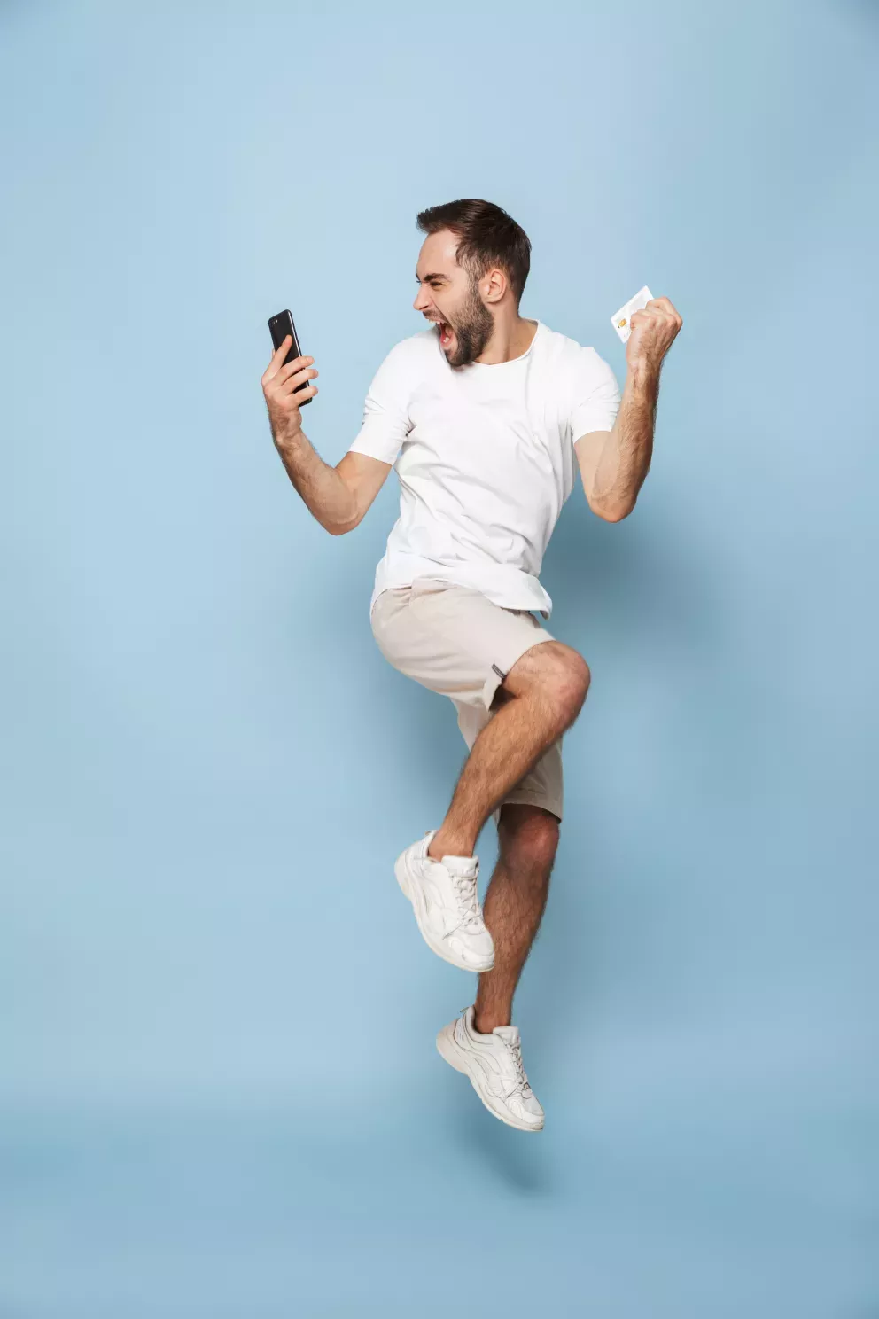 excited man leaping with cell phone and credit card in hand