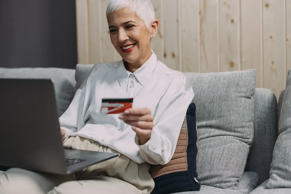 smiling woman holding credit card and using laptop