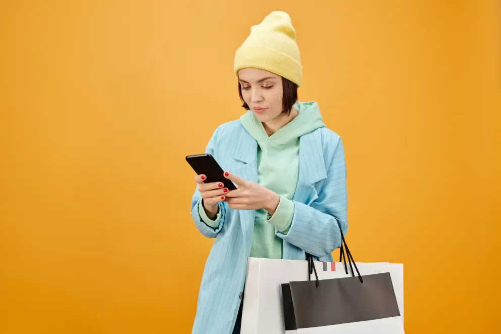 Frau mit Einkaufstüten schaut auf Handy