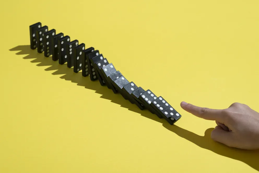 Finger beim Umwerfen von Dominosteinen