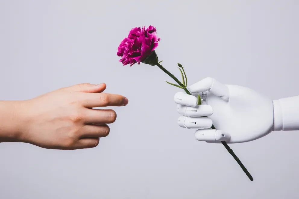 Roboterhand gibt eine Blume an eine menschliche Hand