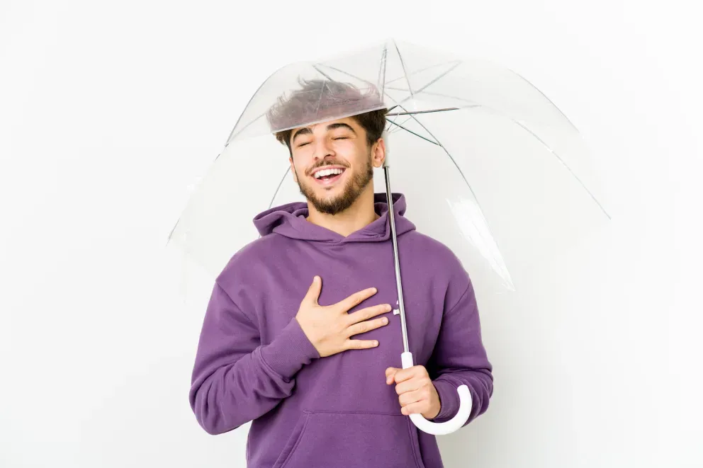 Mann hält Regenschirm mit erleichtertem Gesichtsausdruck