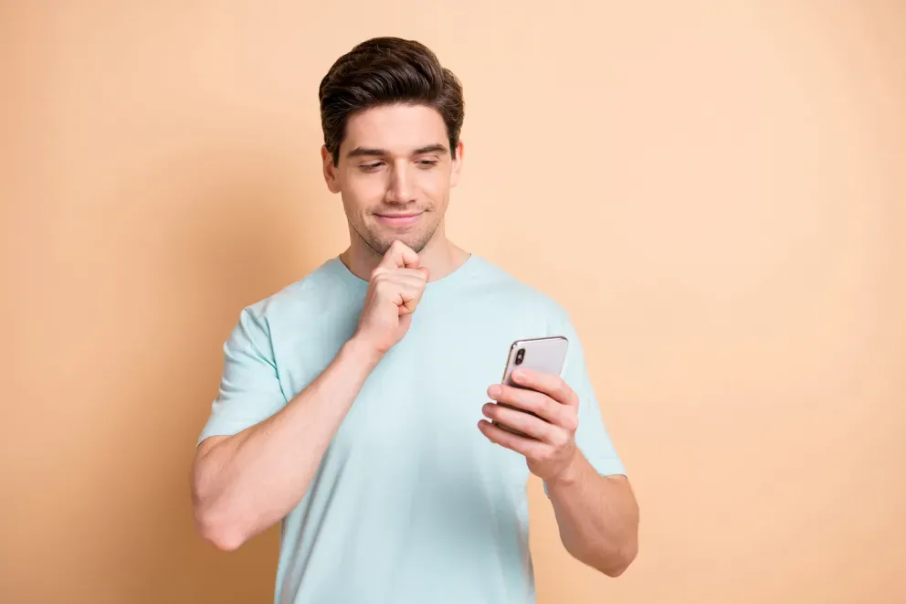 Mann schaut mit fragwürdigem Gesichtsausdruck auf das Handy