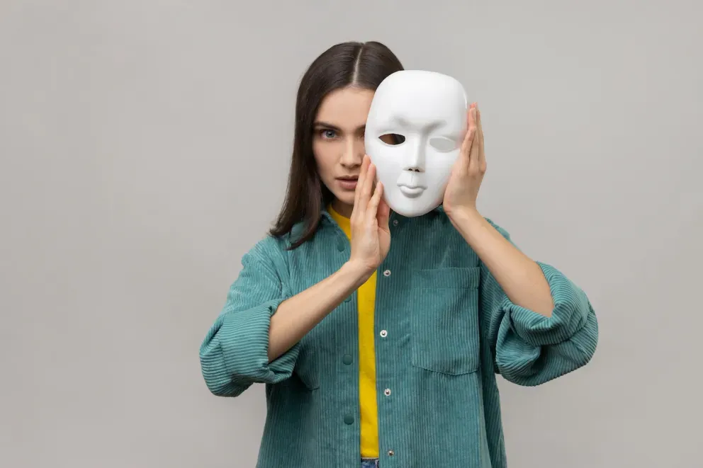 Frau hält weiße leere Gesichtsmaske leicht über ihrem Gesicht