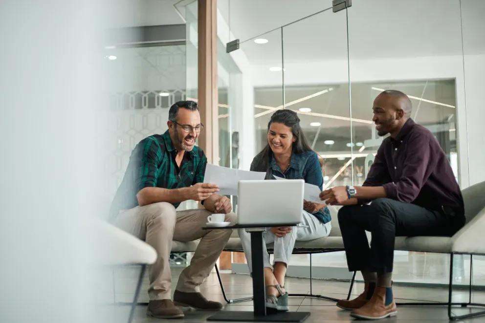 three people working together around a laptop