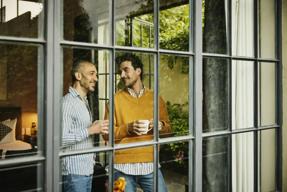 Two men drinking coffee looking out window