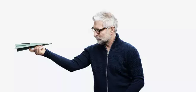 Mann schaut auf ein Papierflugzeug