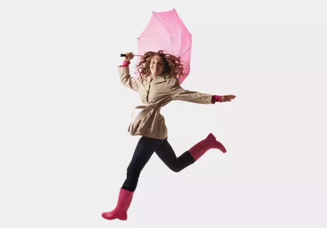 Frau springt mit einem Regenschirm