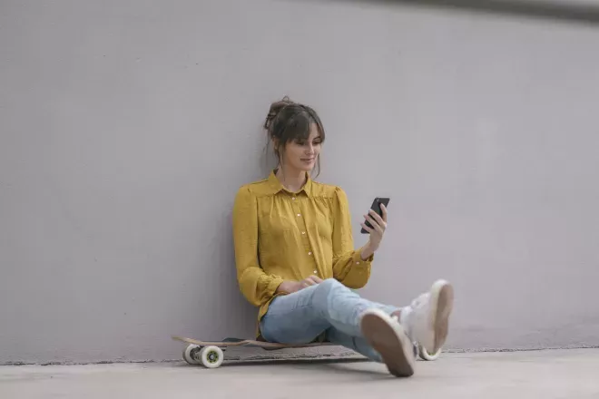 Frau sitzt und schaut auf das Telefon