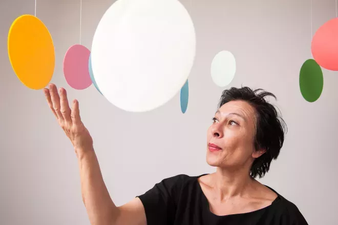 Frau steht in der Mitte hängender Kreiskunstwerke Frau steht in der Mitte hängender Kreiskunstwerke