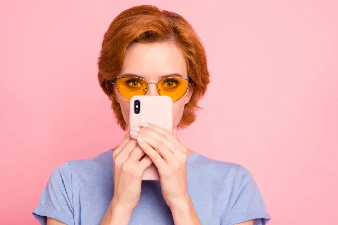 Verdächtige Person mit Brille versteckt sich hinter Handy