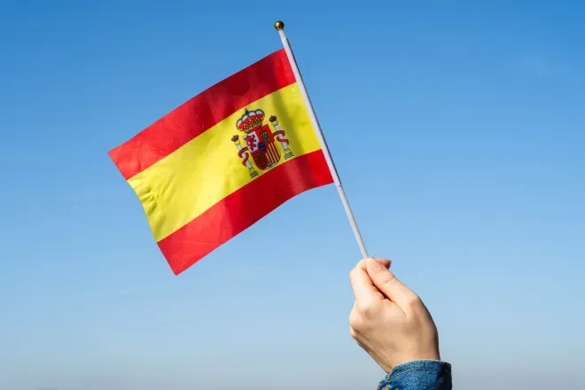 Hand holding Spanish flag in sky
