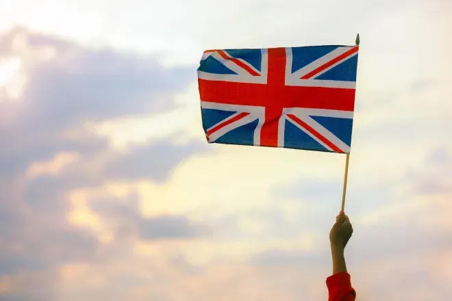 Hand holding UK flag in sky
