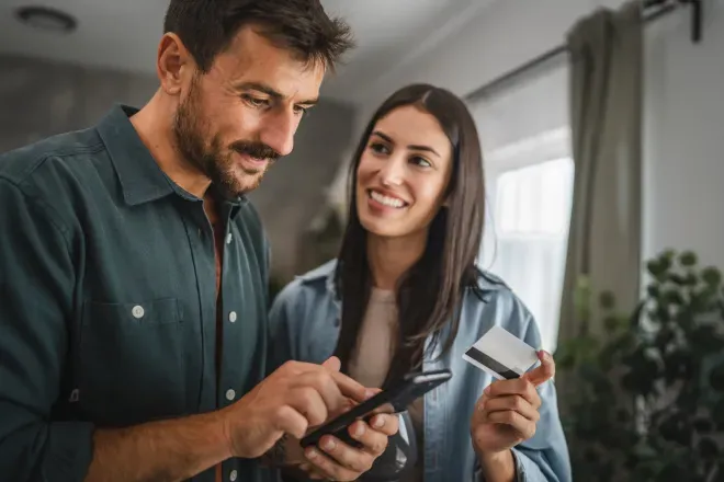 Lächelndes Paar, das drinnen gemeinsam auf ein Smartphone schaut. Lächelndes Paar, das drinnen gemeinsam auf ein Smartphone schaut.