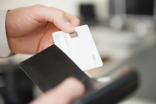 Eine Hand, die eine Kreditkarte hält, die aus einem Portemonnaie kommt Eine Hand, die eine Kreditkarte hält, die aus einem Portemonnaie kommt