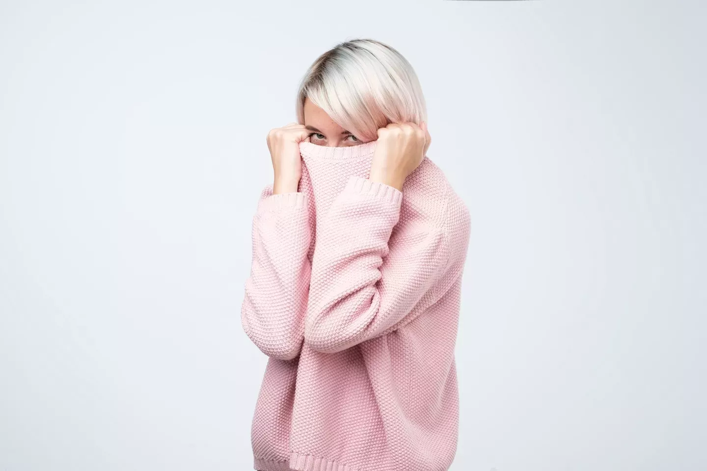 Frau versteckt sich in einem rosa Pullover